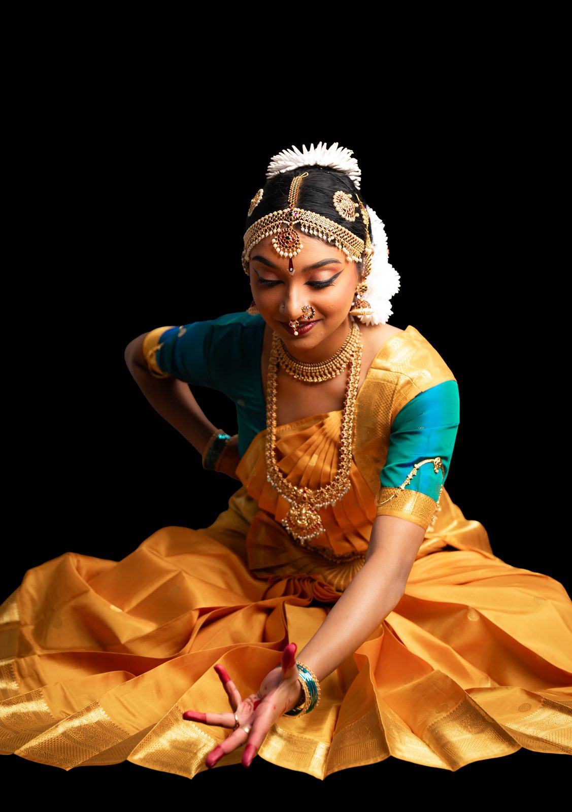 Shriya seated in a dance pose, gold costume