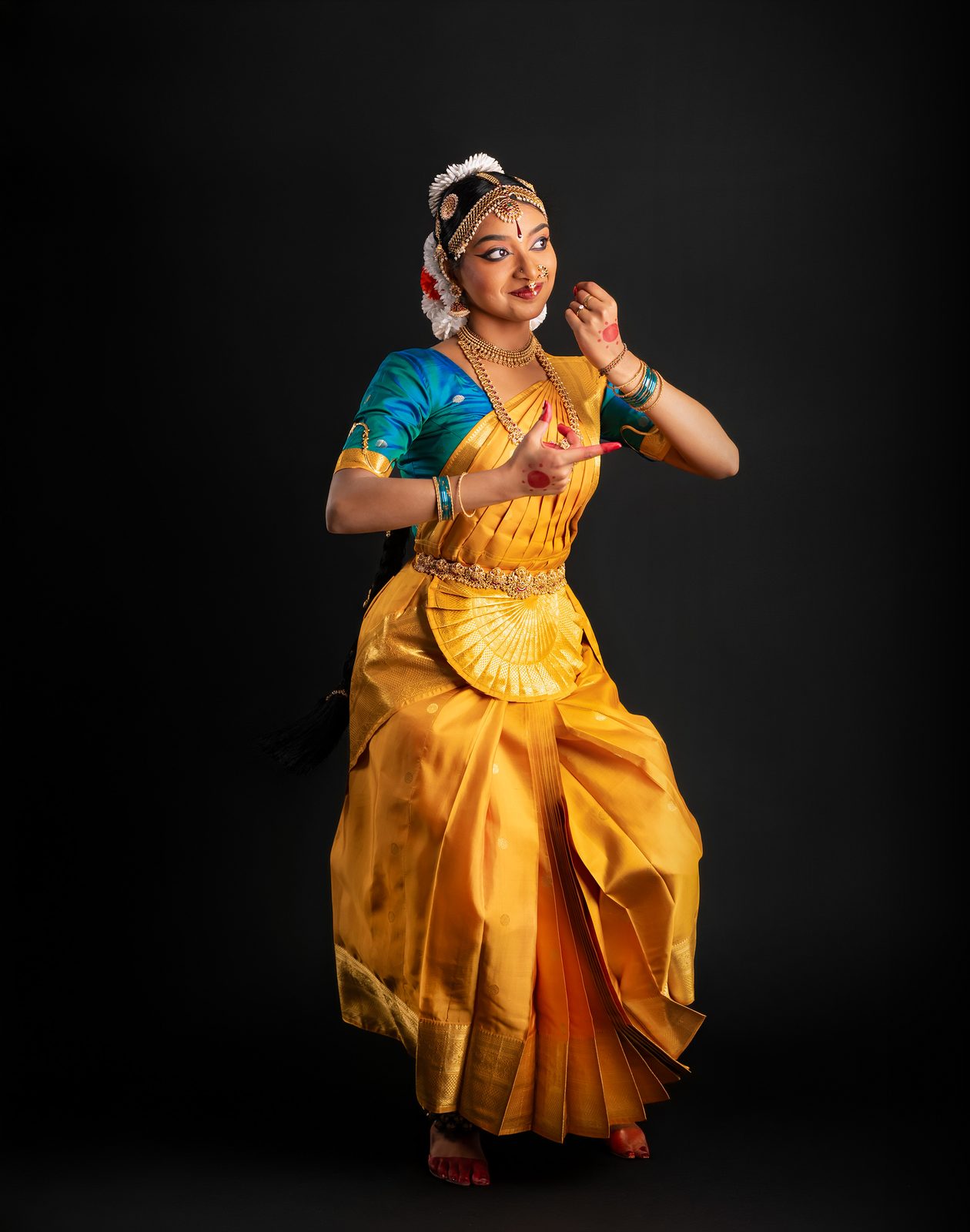 Shriya standing in a dance pose, gold costume